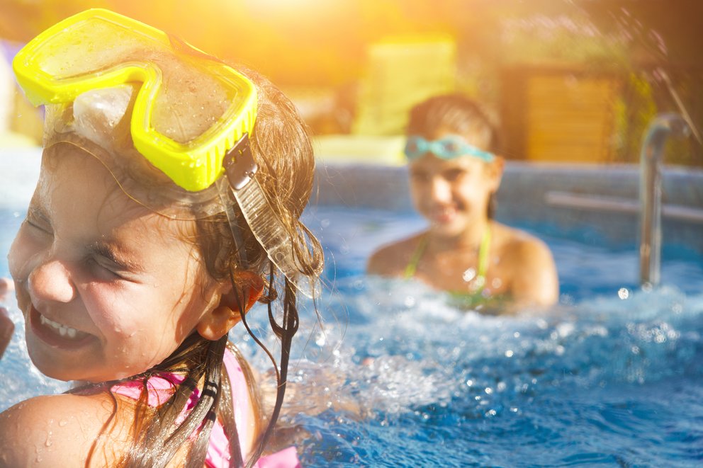 Zoom auf zwei spielende Kinder mit Schwimmbrillen im Wasser.